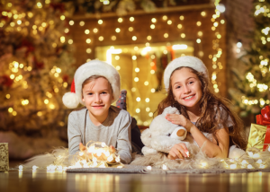 Children laying on floor in front of holiday lights and tree.