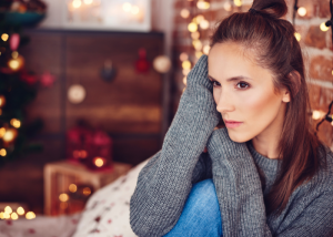 Sad woman sitting in chair with holiday background