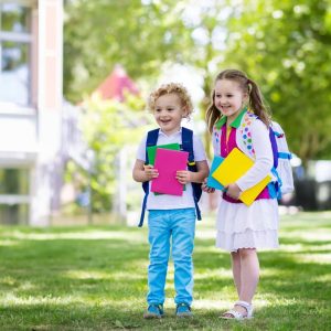 A boy and girl holding books and backpacks